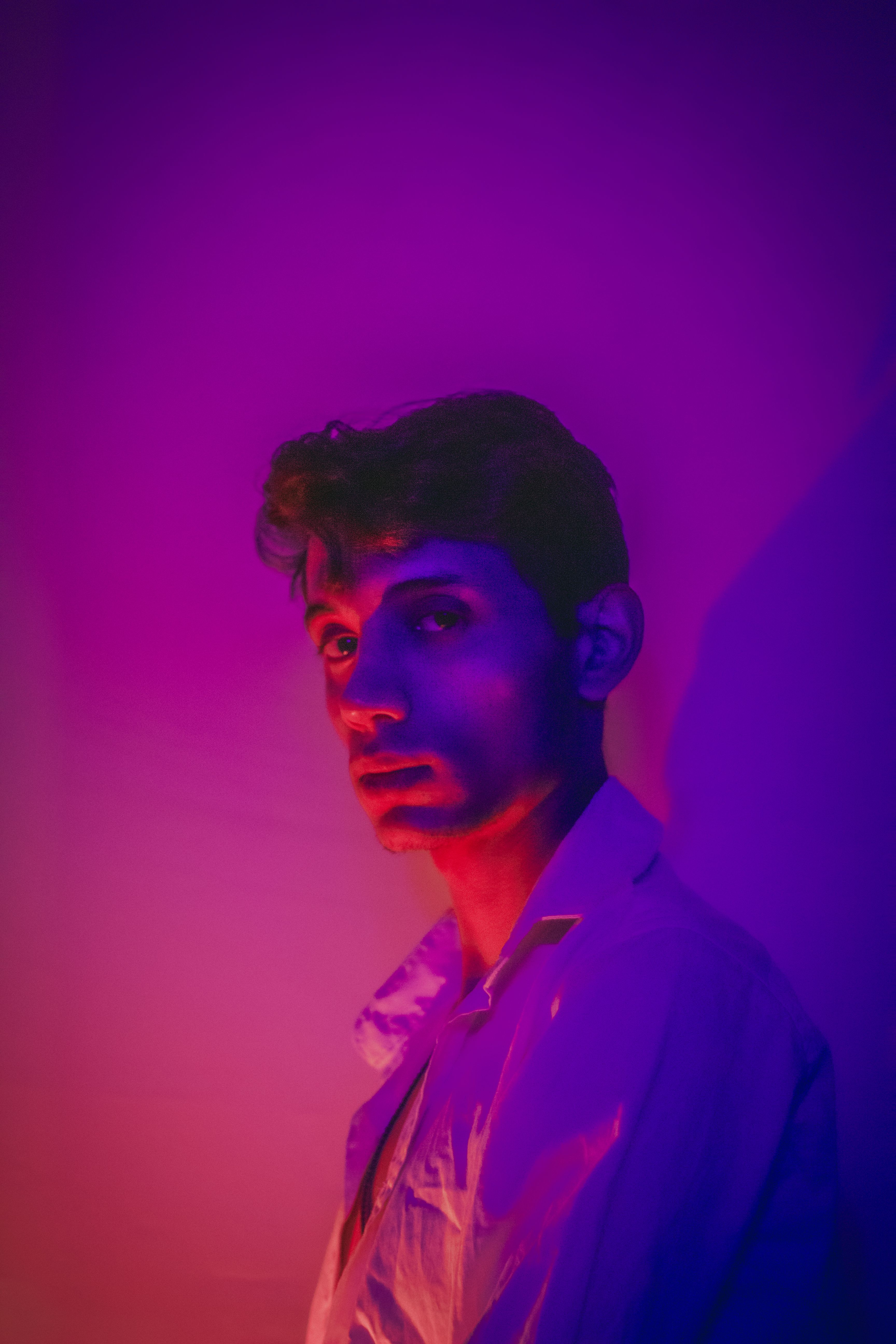 A striking portrait of a man illuminated by vivid neon lighting casting purple and pink hues.