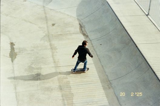 Skateboarder performing tricks at a skate park captured from above, showcasing urban sports culture.