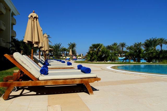Scenic view of luxurious poolside loungers at a tropical resort under clear blue sky. Related image for Hospitality in Africa: Why Independent Hotels Are Investing Now.