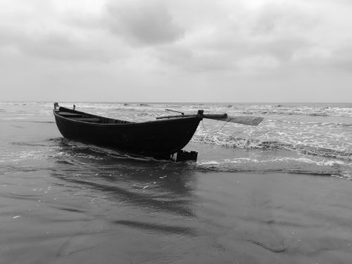 Free A solitary boat rests on the calm shore of Mandarmani Beach, West Bengal, India. Stock Photo