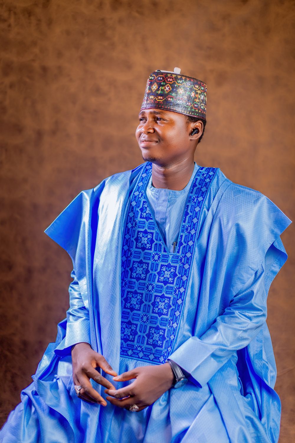 Man in traditional blue attire with embroidered hat