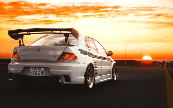 A Mitsubishi Lancer Evo driving on a highway during a vivid sunset, showcasing its sporty design.