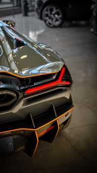 Close-up of a luxury sports car rear in a modern showroom setting.