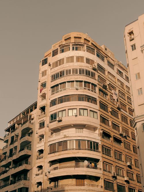 Free A warm-toned image of a multi-story apartment building under a clear sky, featuring urban architecture. Stock Photo