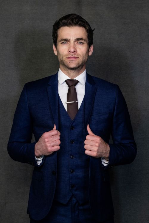 Free Portrait of a confident man in a blue suit against a dark background. Stock Photo