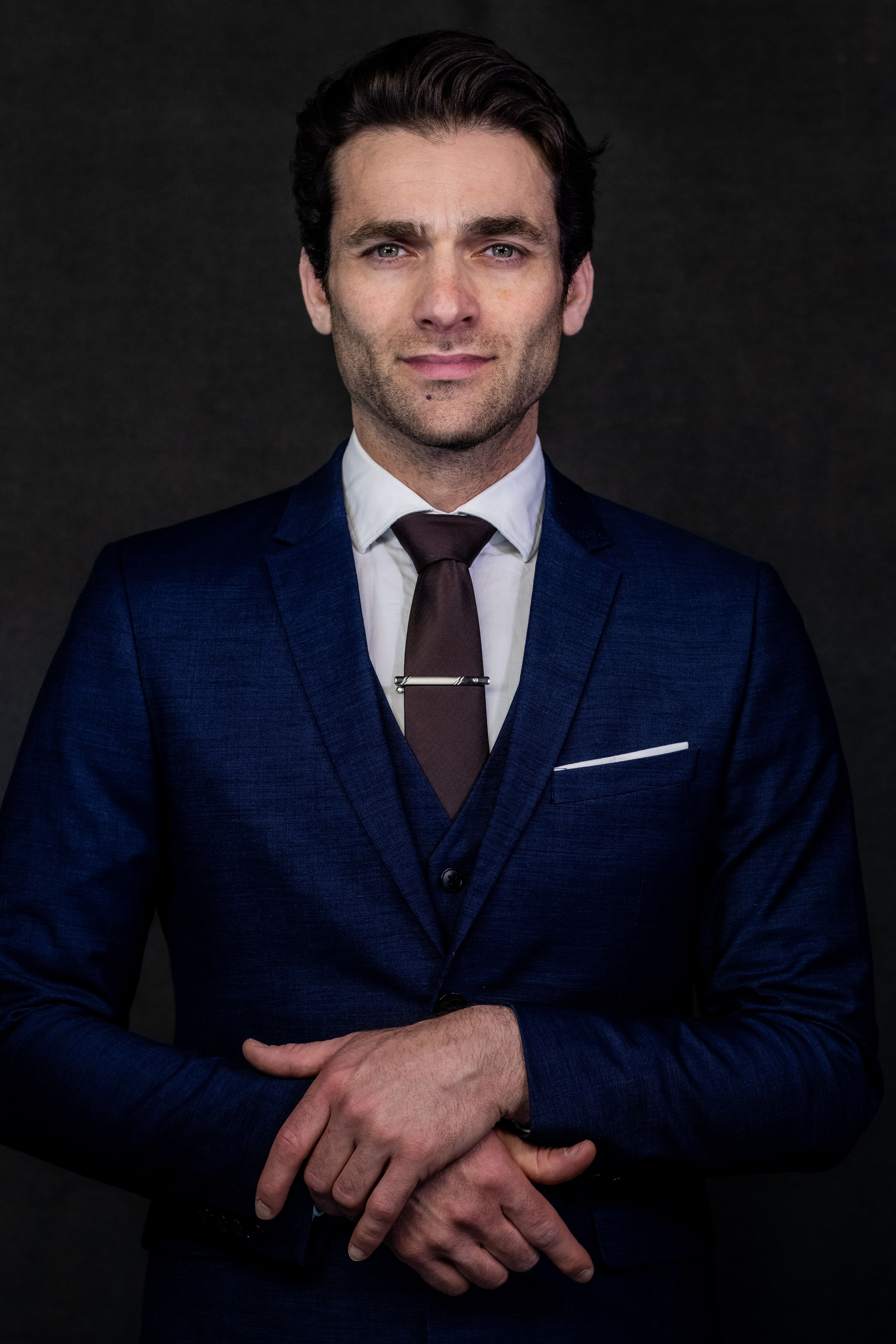 Confident businessman in a blue suit posing with a neutral background.