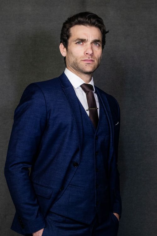 Free Portrait of a confident businessman in a tailored blue suit against a dark background. Stock Photo