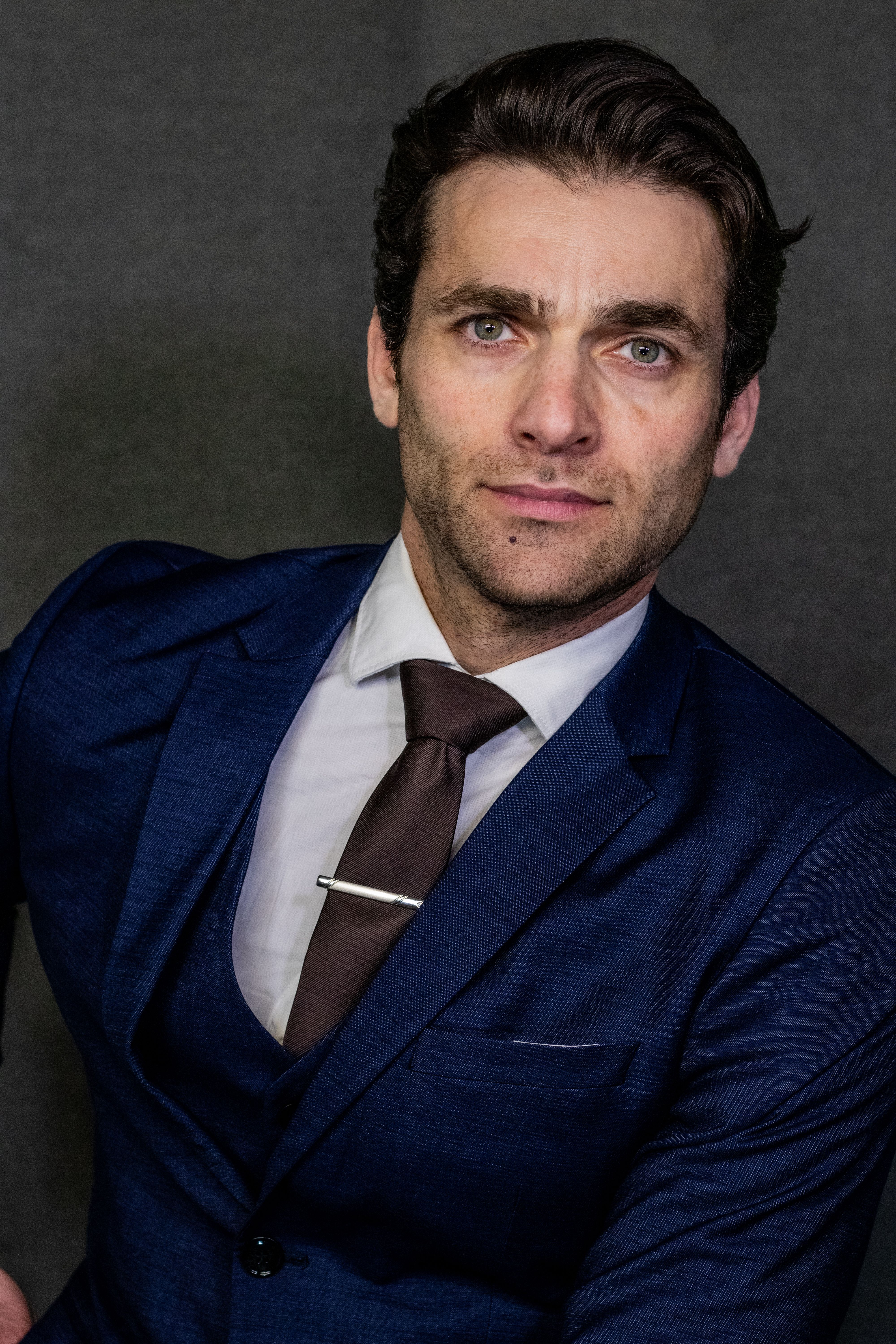 Portrait of a confident businessman in a sharp blue suit with a brown tie.