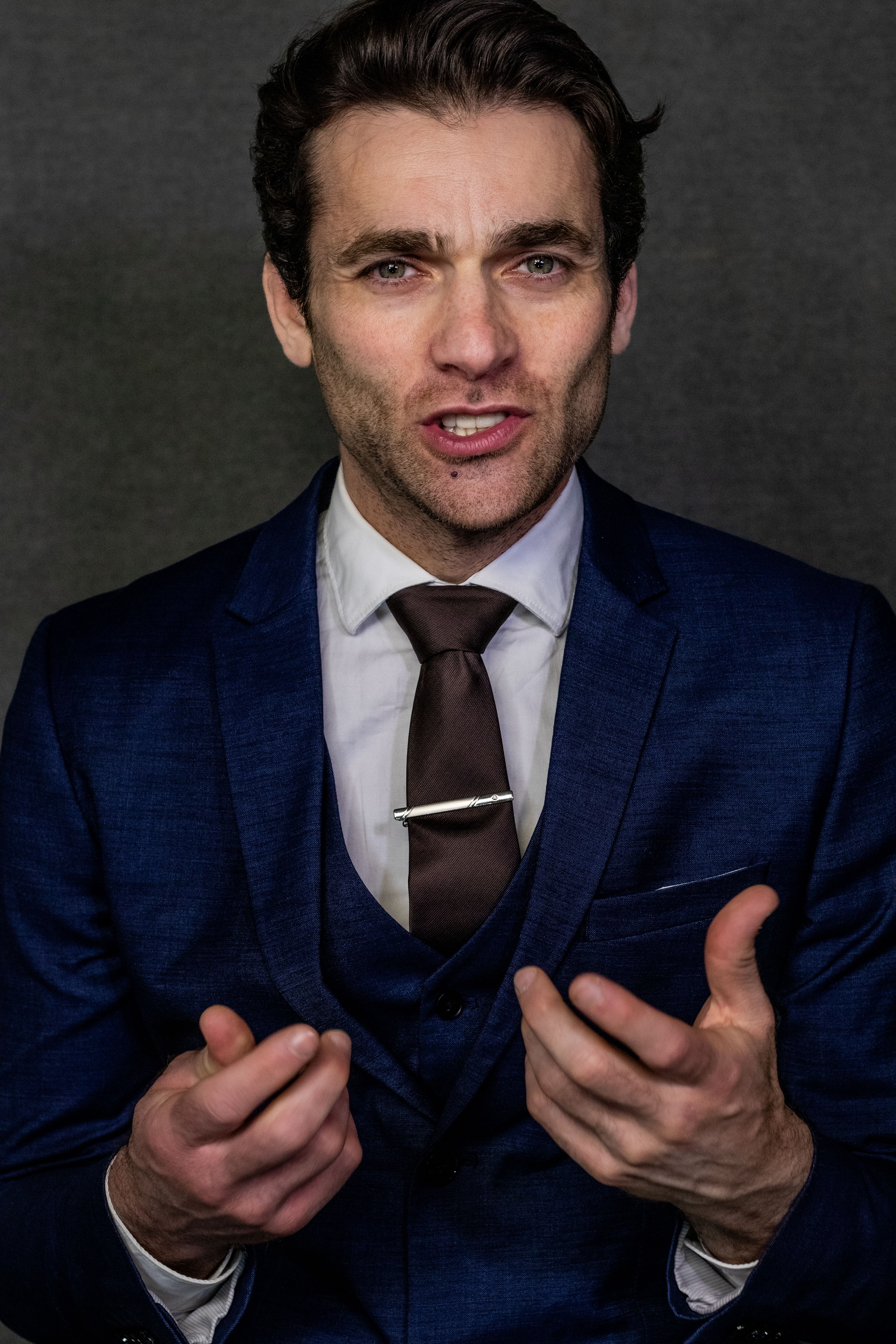 Professional portrait of a businessman confidently gesturing in a blue suit.