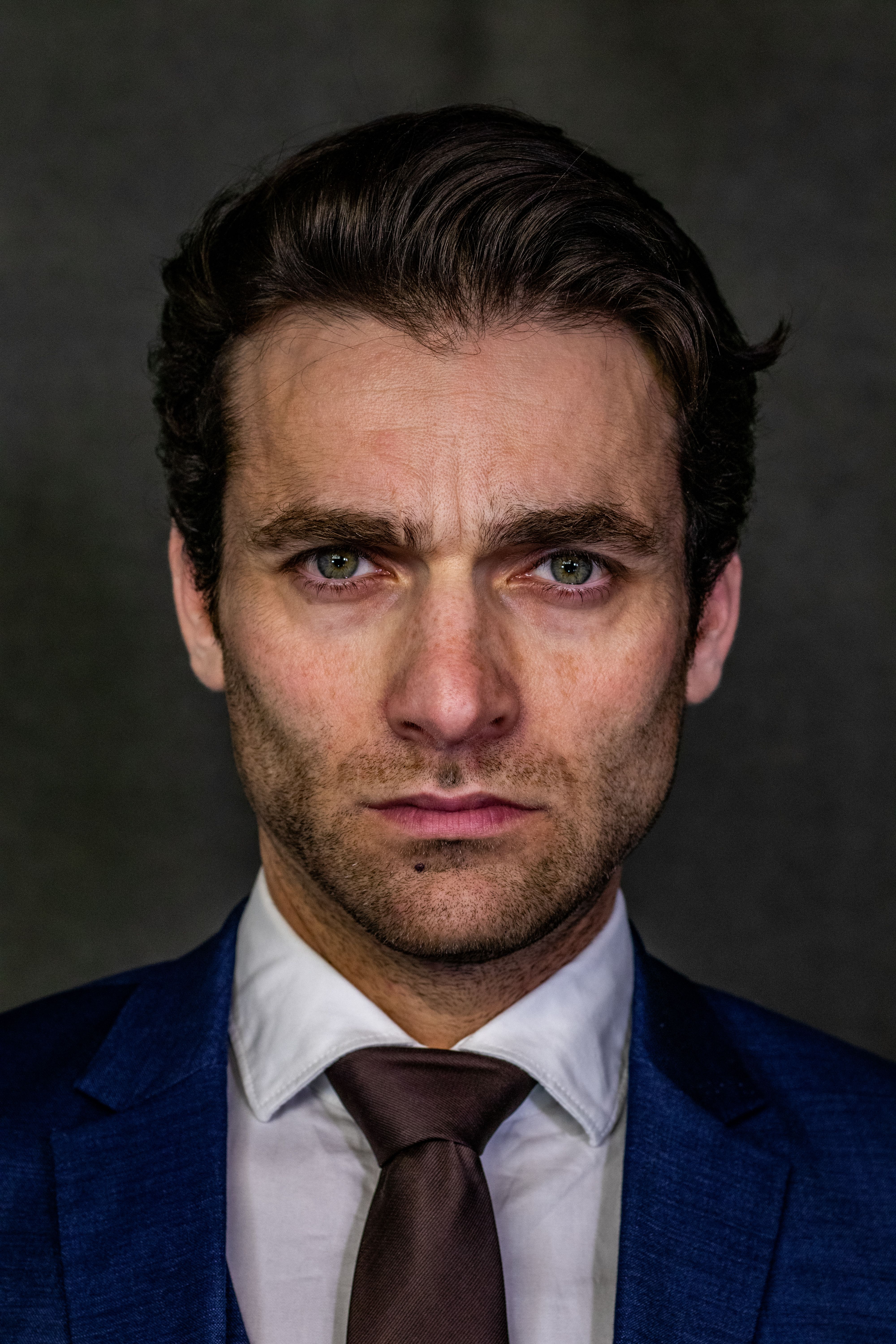 A portrait of a confident businessman in a blue suit with a serious expression.