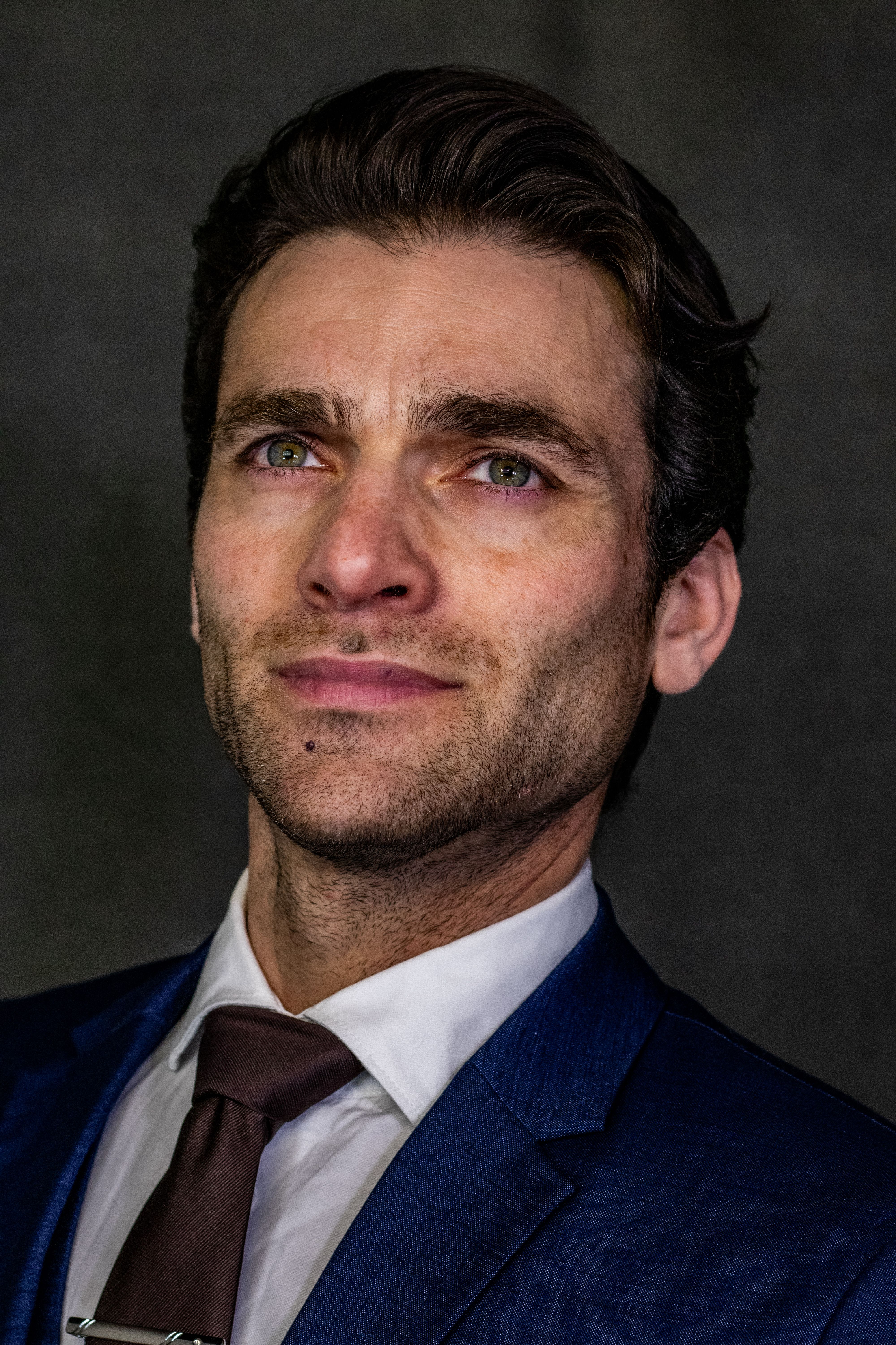 Close-up portrait of a confident businessman in a blue suit, looking upward.