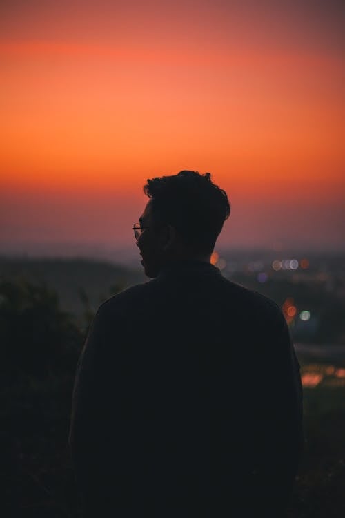 Silhouette of Man Wearing Eyeglasses Standing during Sunset