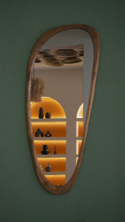 Free Curved mirror reflecting an elegant interior with decorative shelves and ambient lighting. Stock Photo