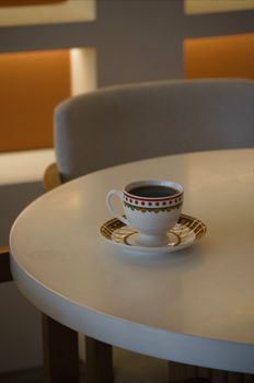 Artistic view of a coffee cup on a round table in a modern Turkish cafe setting.