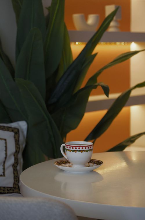 Free A serene coffee cup on a table with lush indoor plants and warm lighting in a cozy interior. Stock Photo
