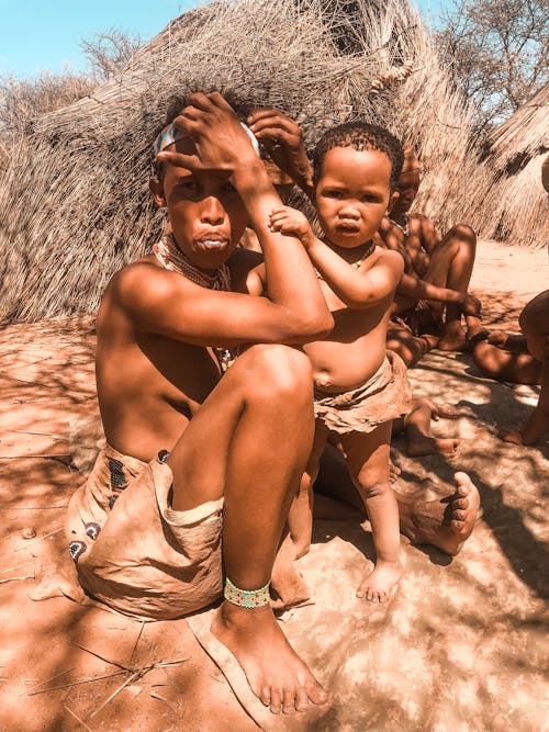Женщина с ребенком, сидящим на песке
