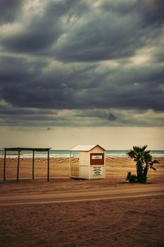 A lifeguard hut on a deserted beach with dramatic storm clouds overhead