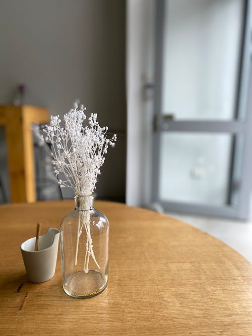 갈색 나무 테이블에 투명 유리 꽃병에 흰색 꽃