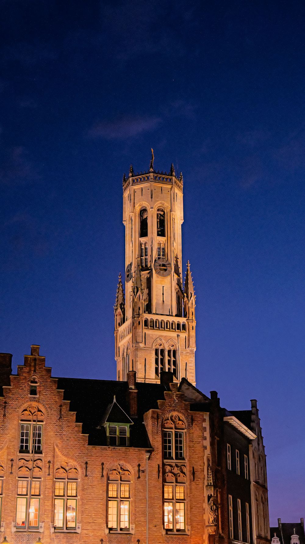 Turnul Belfort din Bruges la ceas de seară, luminat pe cer albastru