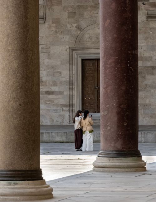 Free Capture of two people exploring between large stone columns of a historical building. Stock Photo