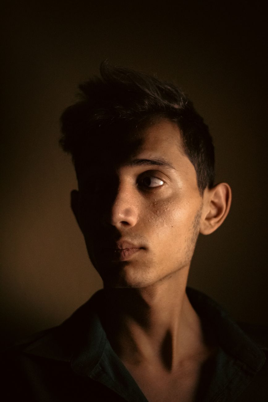 Moody side profile portrait of a young adult man with dramatic lighting.. moody, side, profile