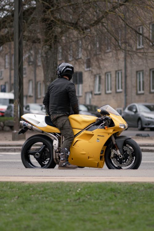 Free A motorcyclist on a yellow Ducati bike waits at a city intersection. Stock Photo