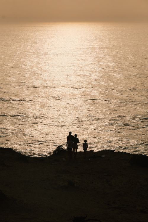 Free Silhouette of a family by the ocean during a serene sunset, creating a peaceful scene. Stock Photo