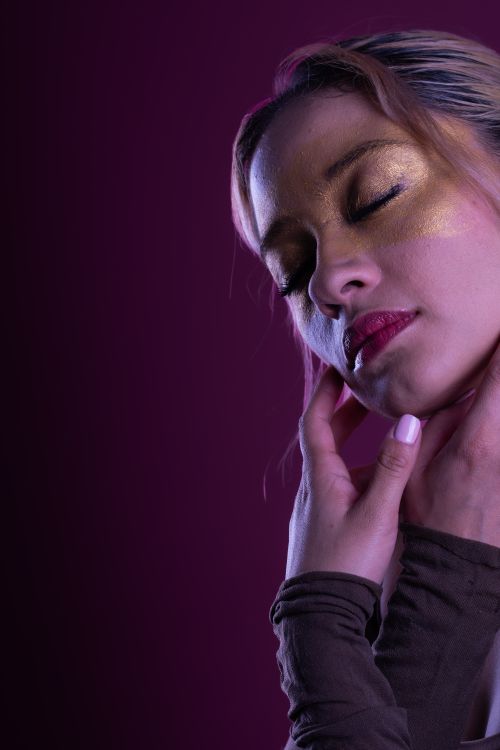 Free Elegant portrait of a woman with gold eye makeup against a deep magenta background. Stock Photo