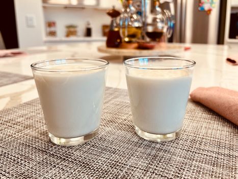 Two glasses of fresh milk on a modern kitchen table with a cozy setting.