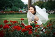 身着白色礼服的新娘在郁郁葱葱的花园里快乐地与玫瑰合影