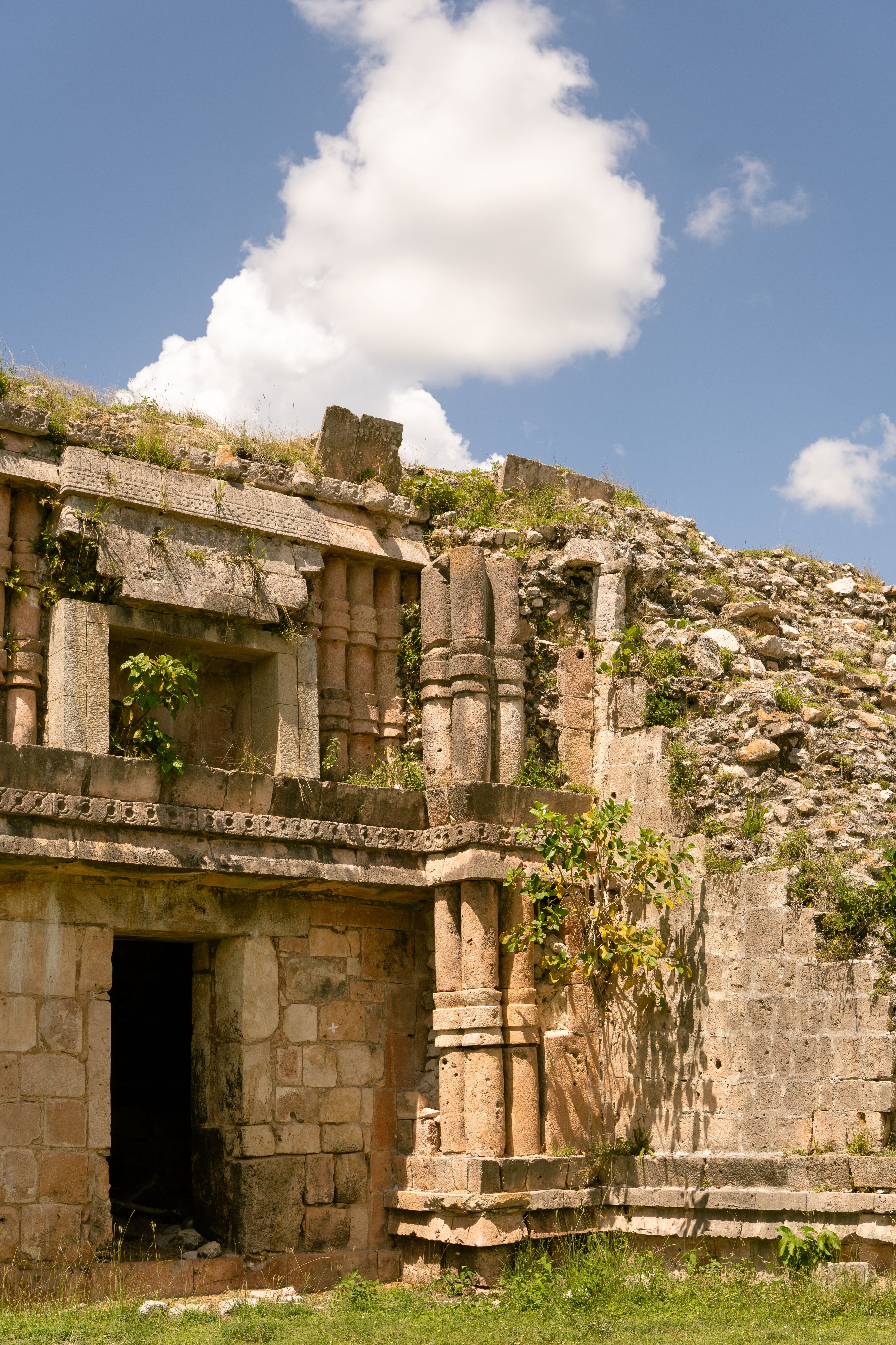 Historical Mayan ruins at Chacmultún, Yucatán, Mexico, under a bright blue sky.