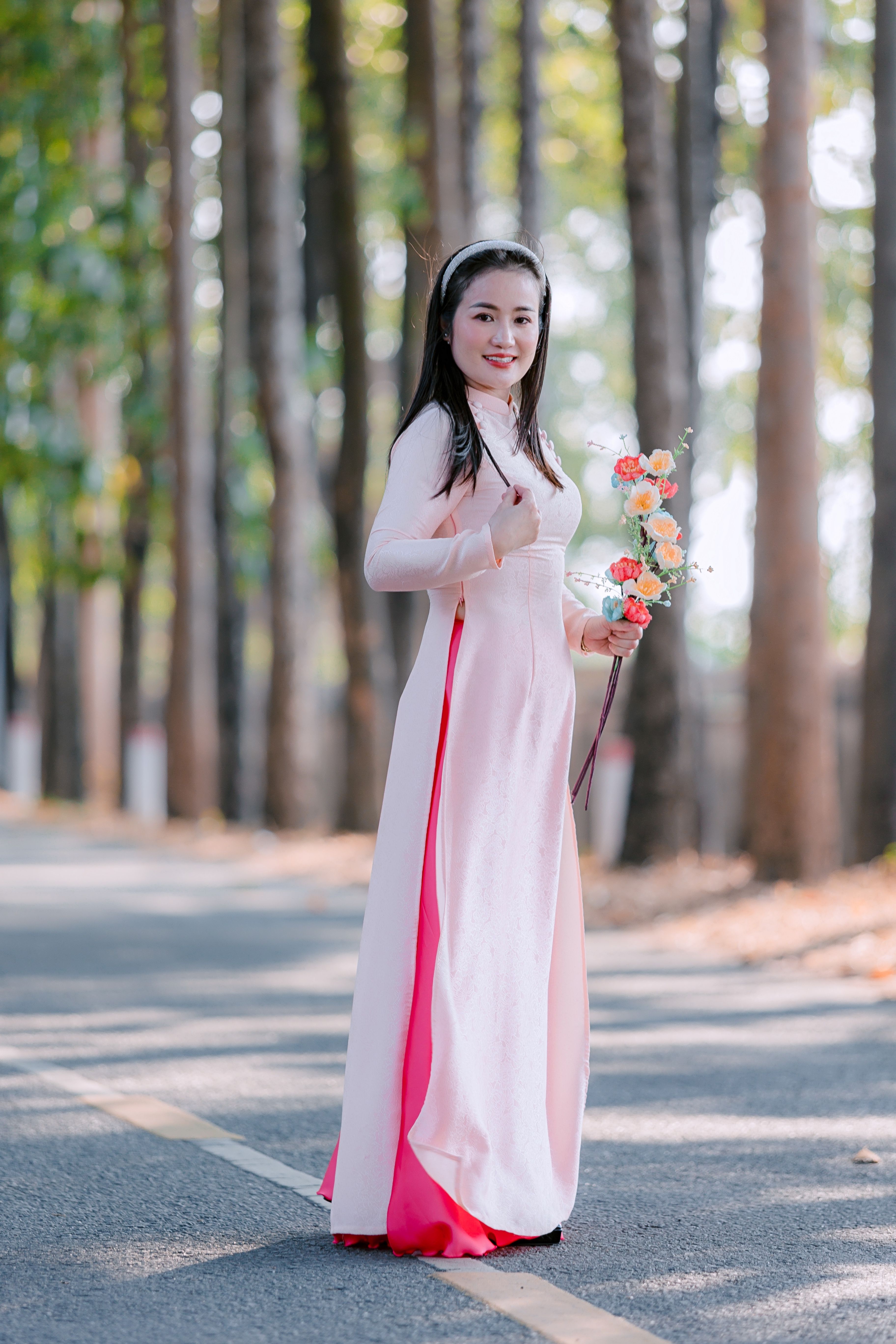 Woman in Traditional Dress Holding Flowers in Forest · Free Stock Photo