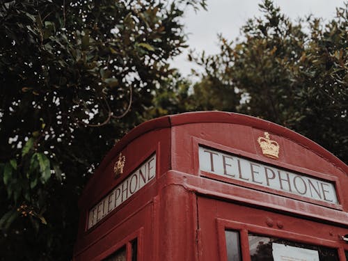 Red Telephone Booth Near Green Trees