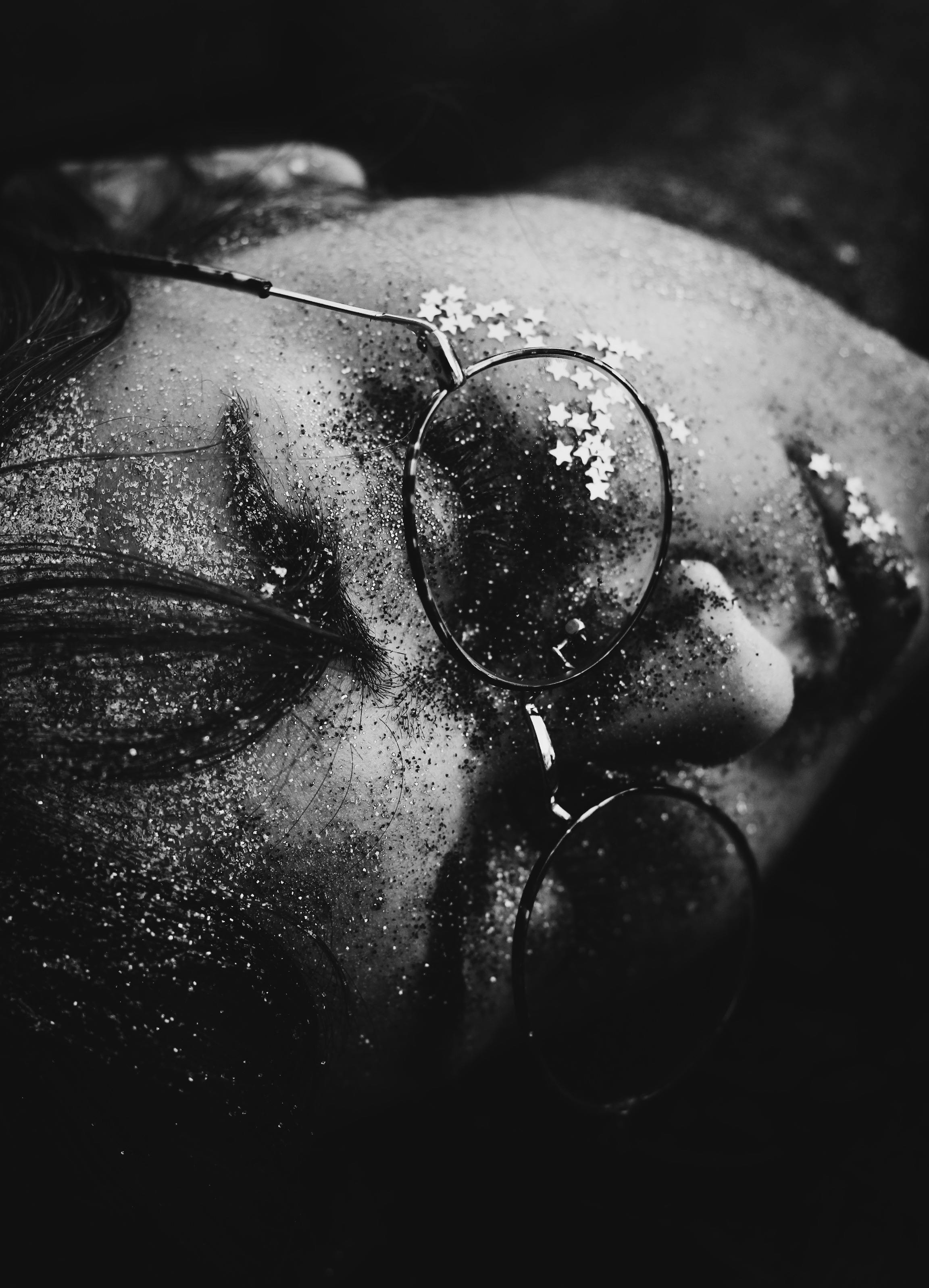 一张戴着闪光灯和眼镜的女人脸的黑白特写肖像，捕捉到艺术和梦幻的氛围