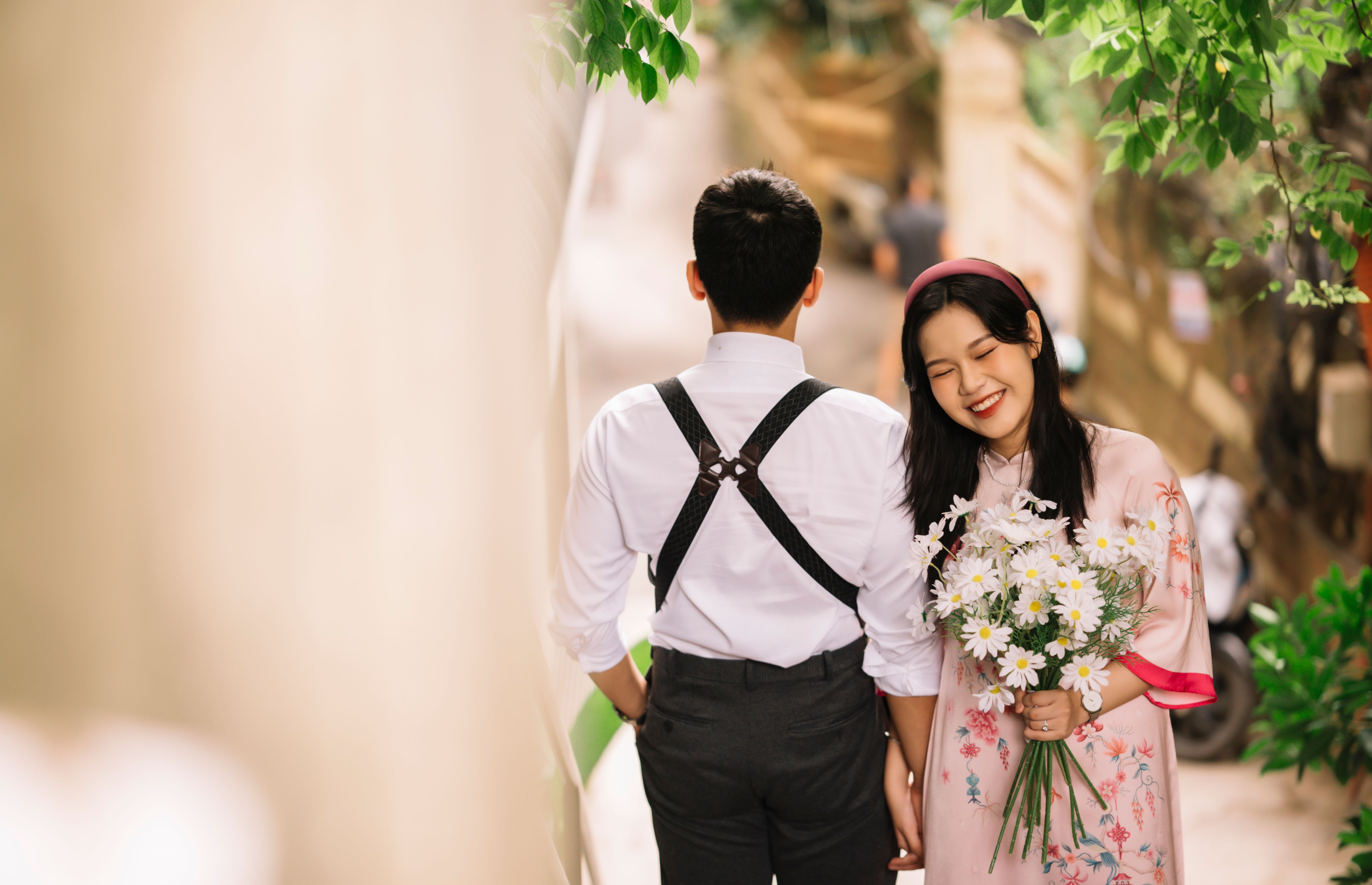 A romantic outdoor scene with a couple holding hands, featuring daisies and a joyful expression.