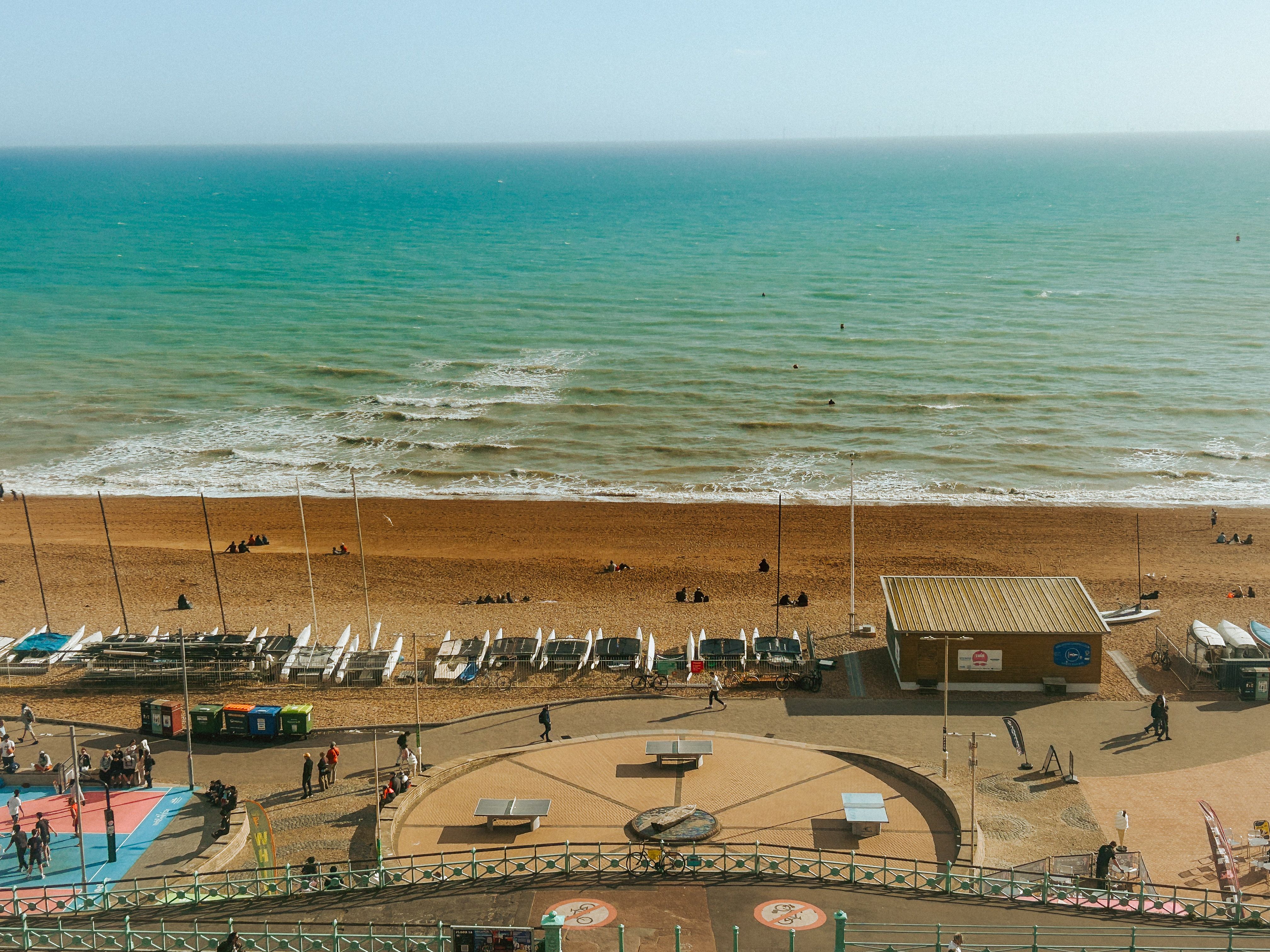 Aerial view of Brighton Beach with people and azure ocean under a sunny sky.