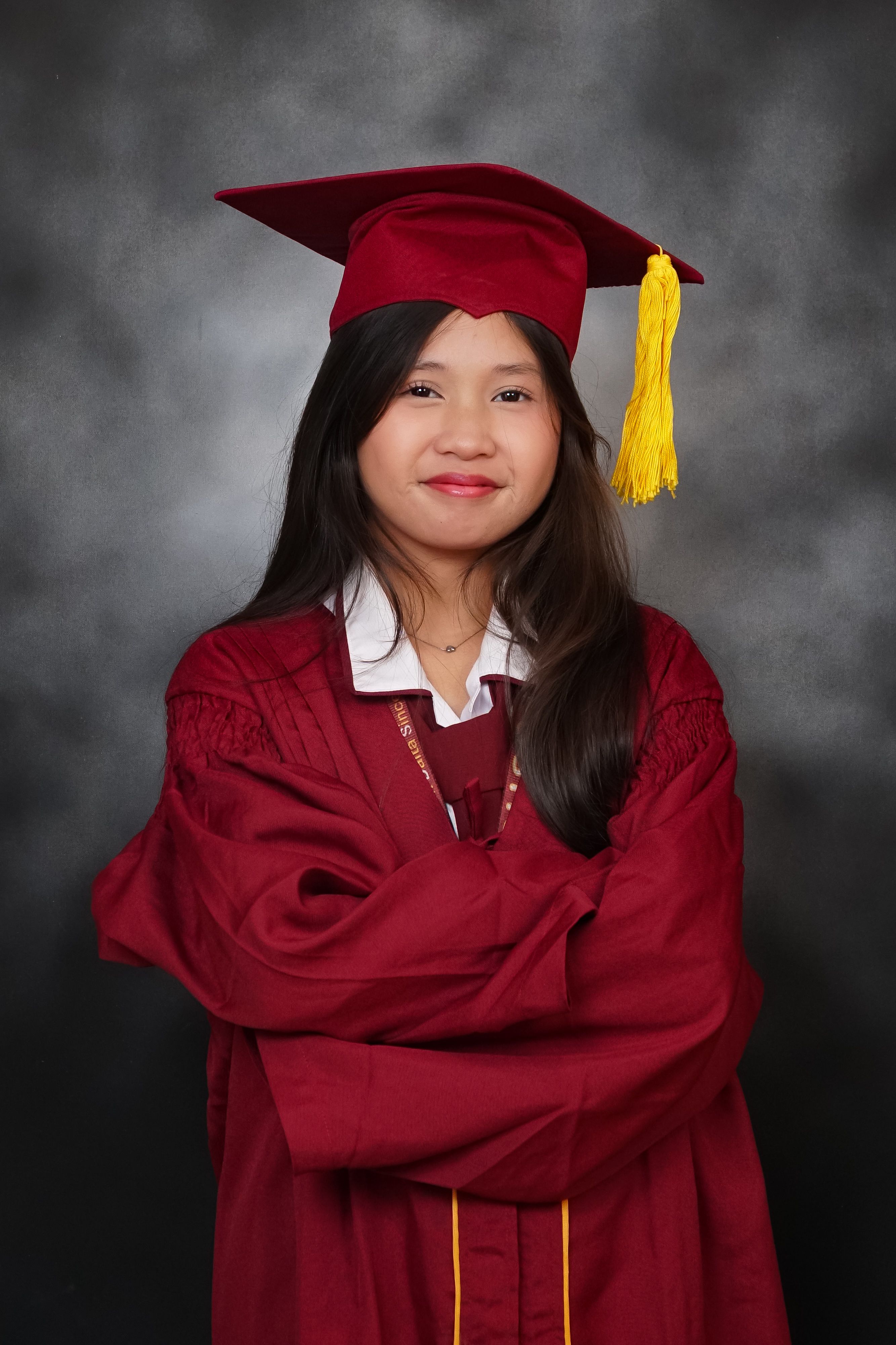 Smiling young graduate in red gown with tassel, showcasing academic achievement.