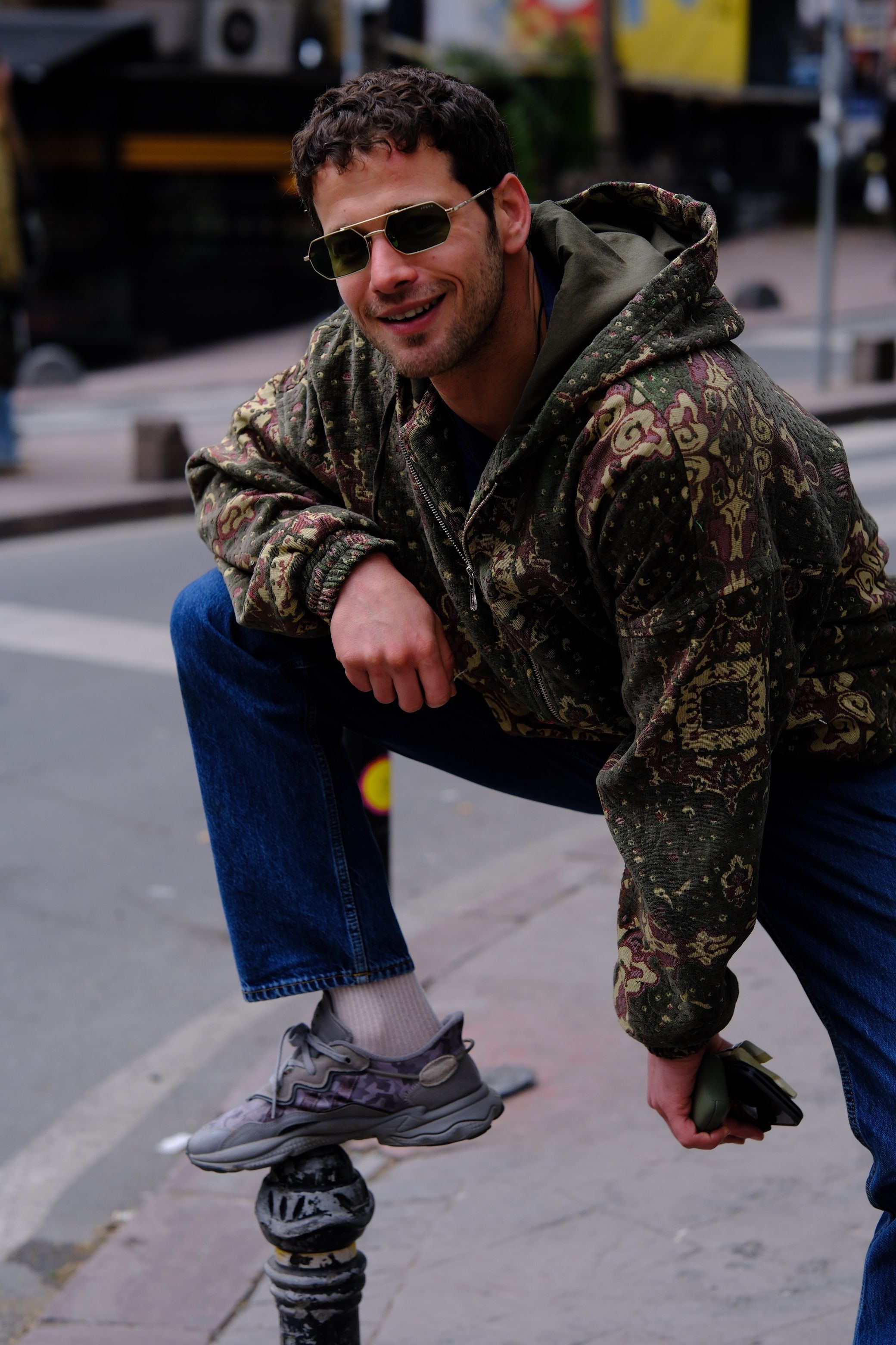 Casual portrait of a man posing on a street corner, showcasing urban fashion and relaxed style.