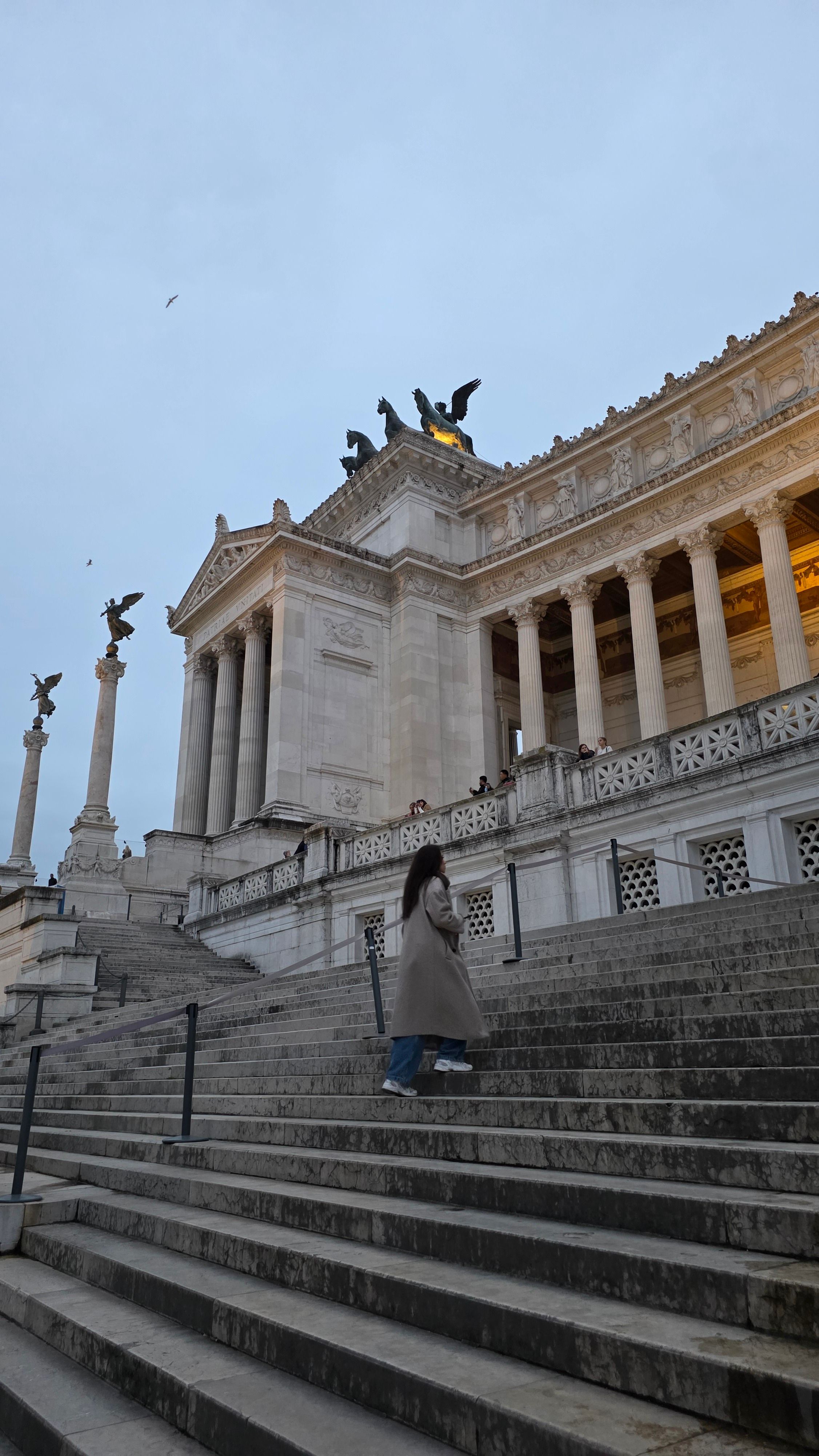 A person ascends the stairs of the iconic Altare della Patria in Rome, Italy, during daytime.
