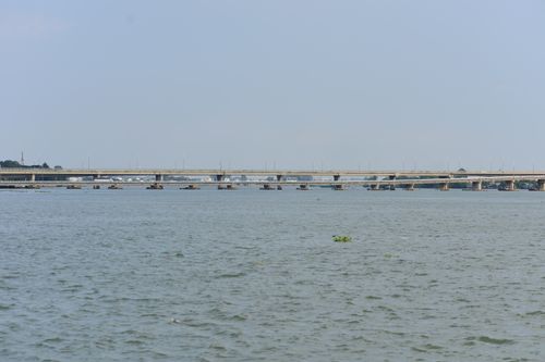 Free A modern bridge spans over a wide river under a clear blue sky, offering a scenic view. Stock Photo