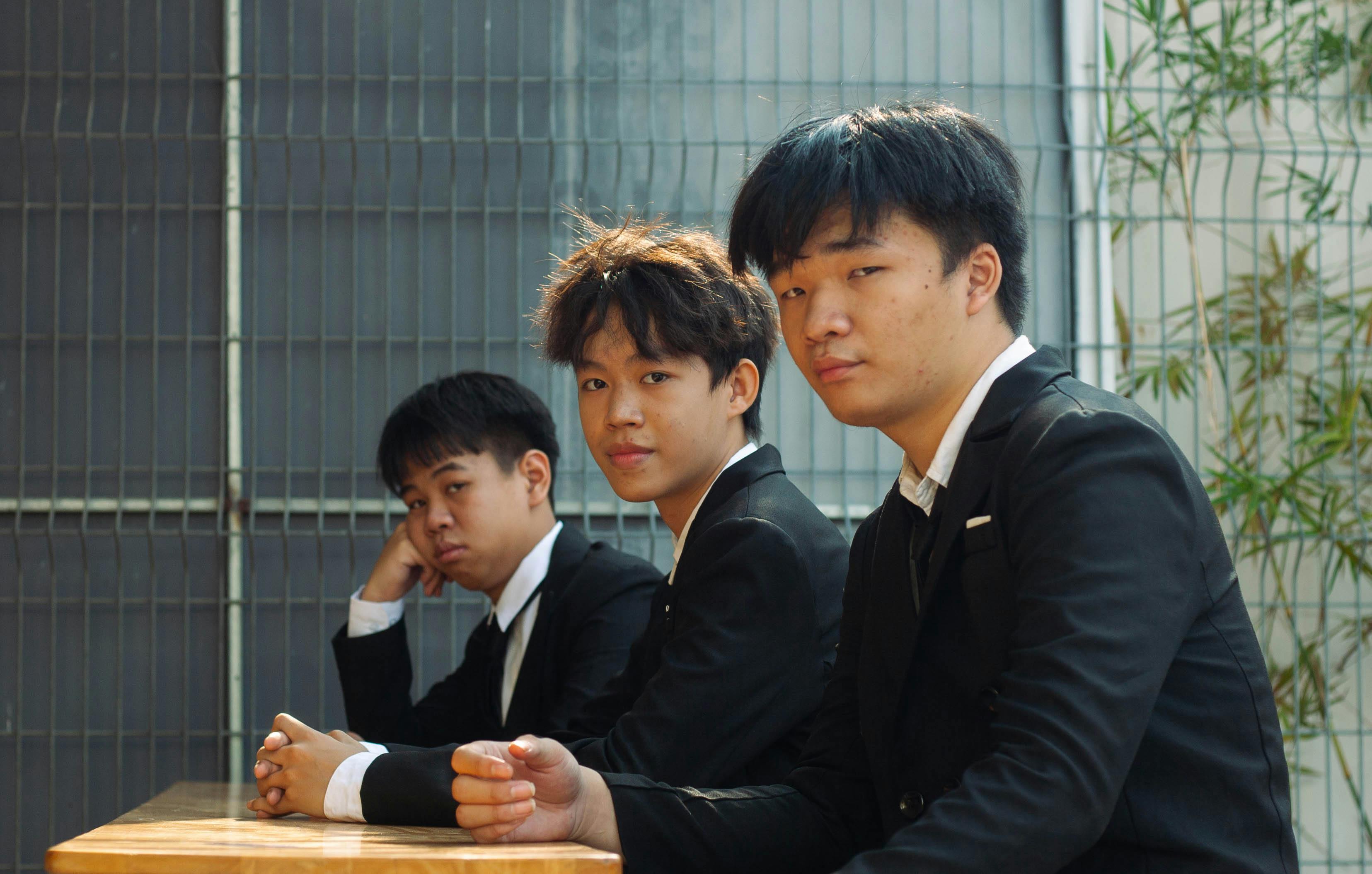 スーツを着た3人の若いビジネスパーソンが、屋外でビジネスについて話し合っている。