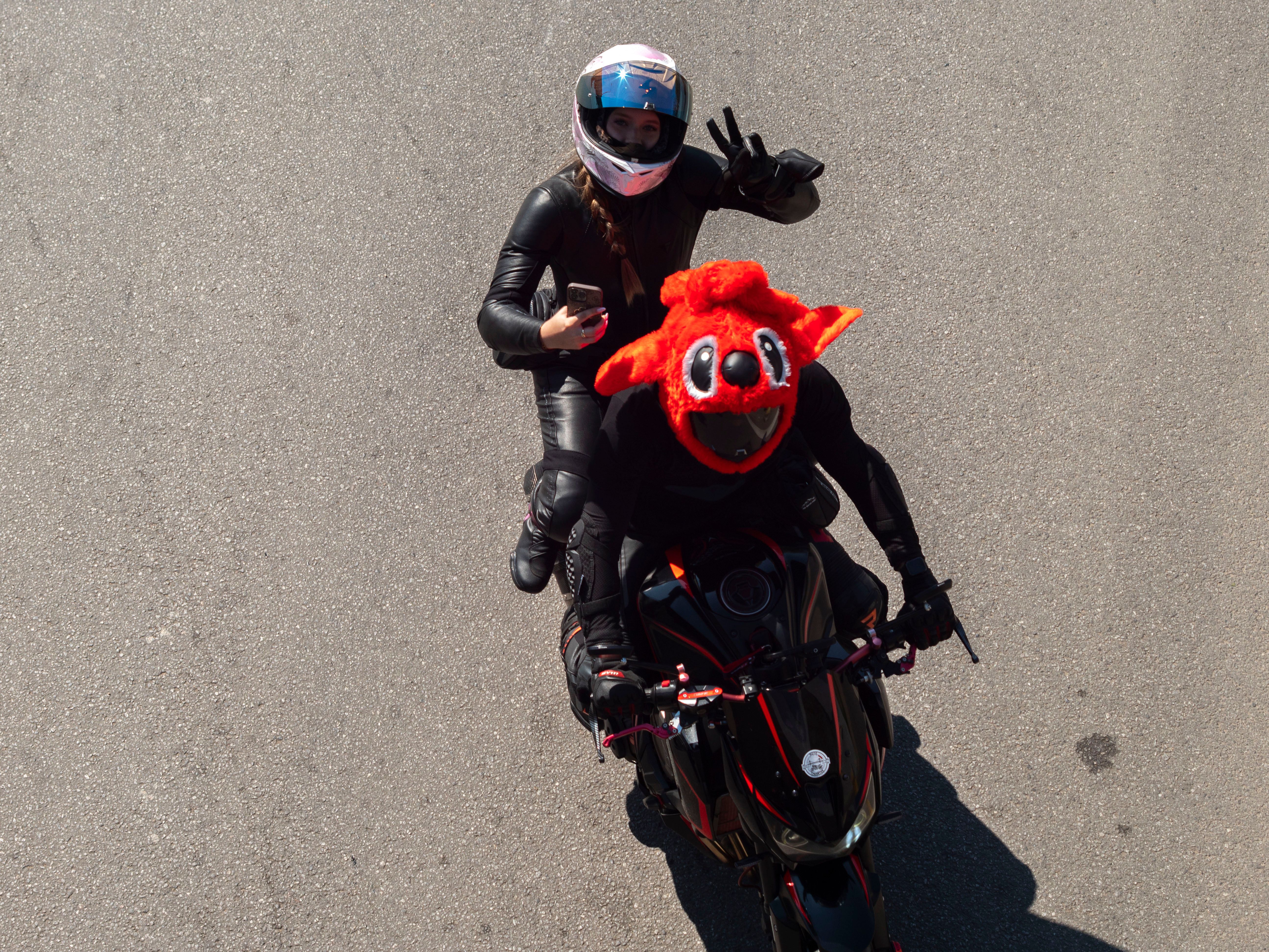 Aerial view of two bikers, one in a red mascot costume, riding a motorcycle on a sunny day in Wrocław.