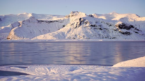 無料 水域近くの雪に覆われた山 写真素材