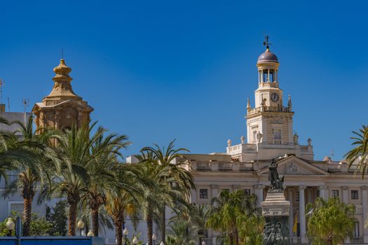 Cádiz Town Hall with iconic architecture and statue, framed by palm trees under a clear blue sky.