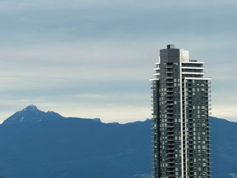 Modern high-rise tower against mountain backdrop in Surrey, BC, Canada.