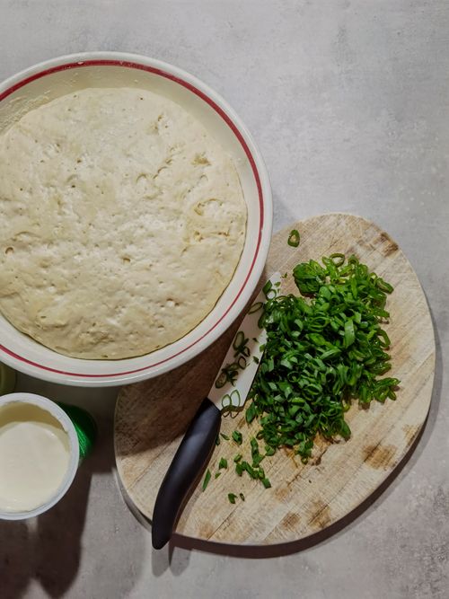 Free High angle view of dough rising in bowl next to freshly chopped scallions on cutting board. Stock Photo