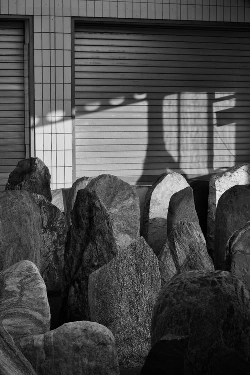 Free Monochrome stones beneath shuttered windows with shadows creating geometric patterns. Stock Photo