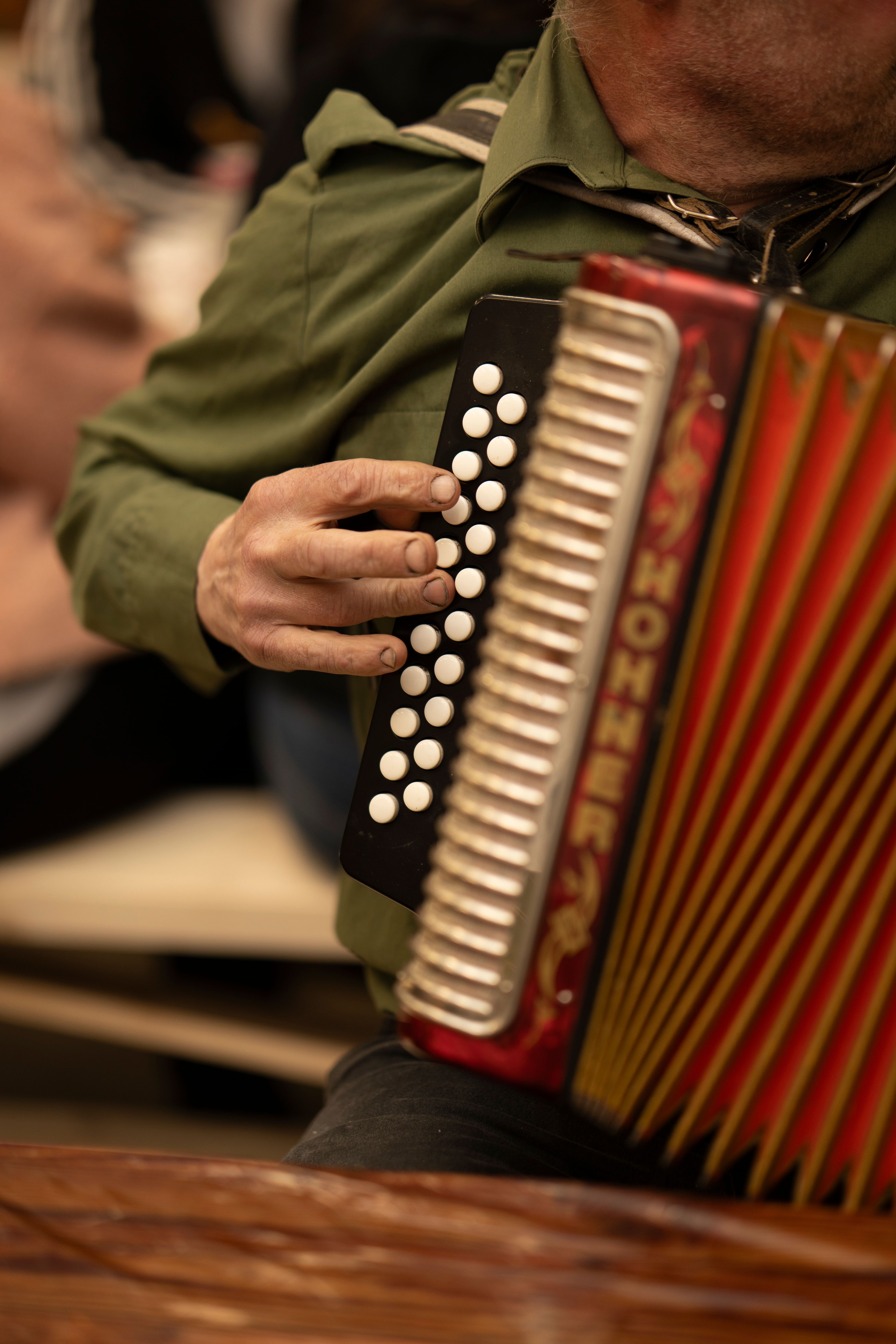 Hands on the buttons of a well-travelled accordion at a session