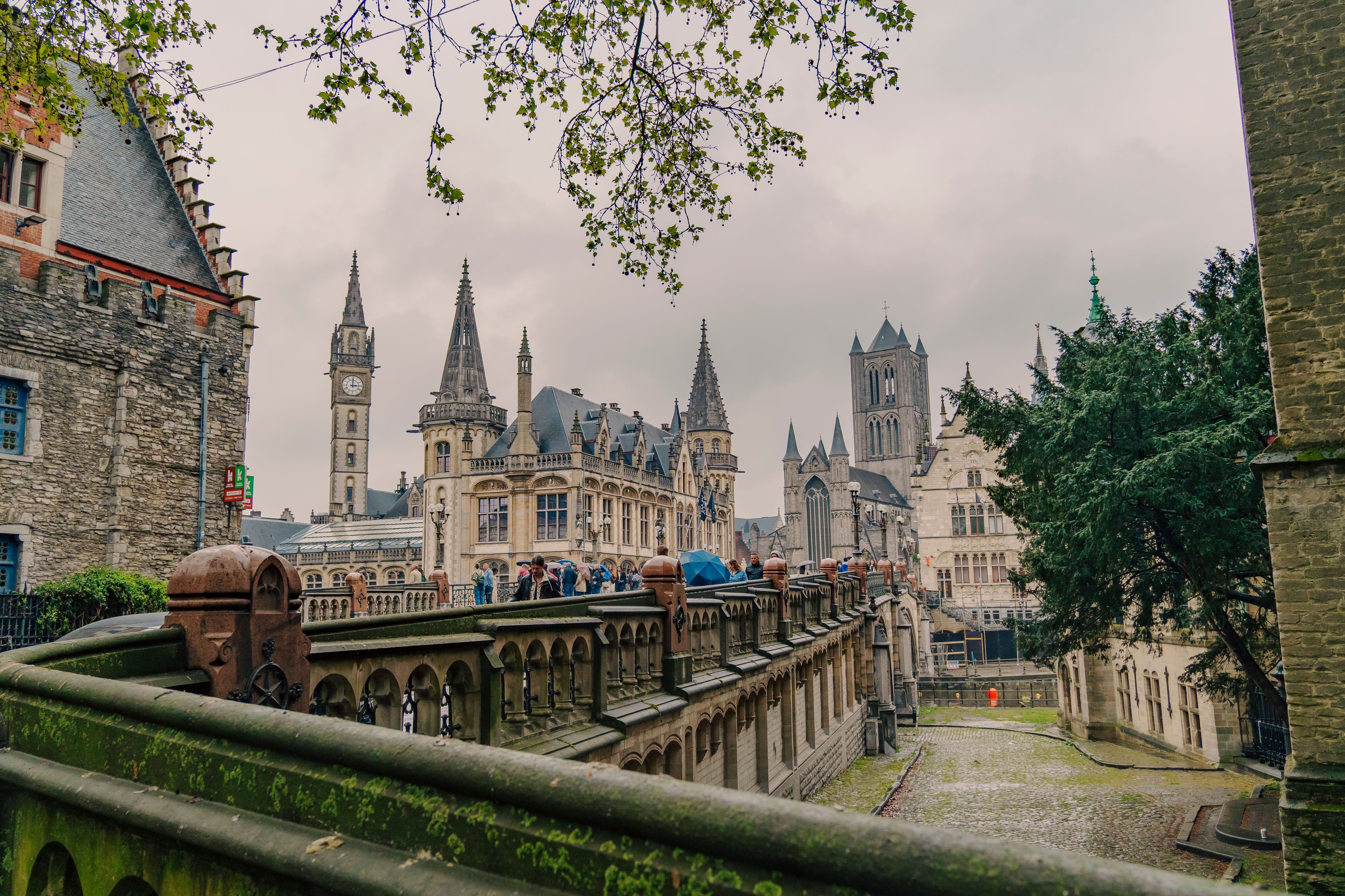 Explore the stunning medieval architecture and iconic belfry towers in Ghent, Belgium, under overcast skies.
