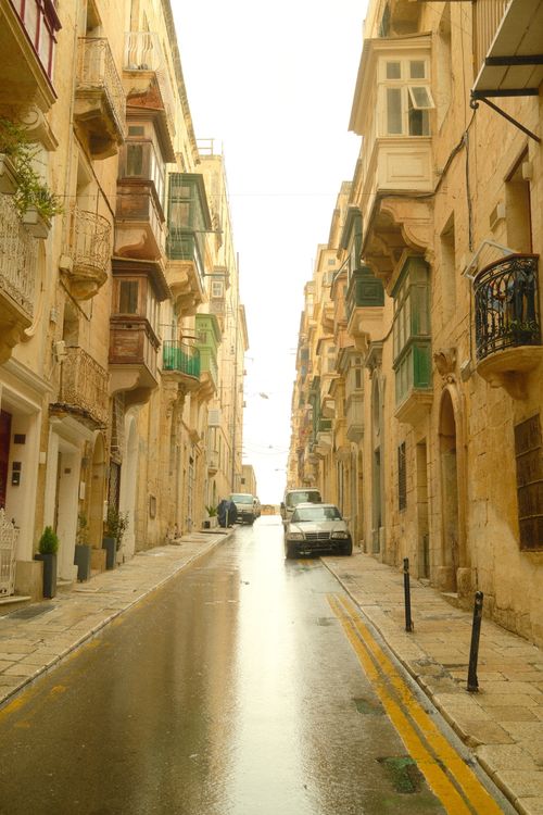 Free Explore a tranquil Maltese street, showcasing traditional architecture, after rainfall with a serene ambience. Stock Photo